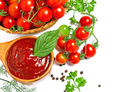 Red tomato sauce in a wooden spoon and ingredients, isolated in whiteの写真素材
