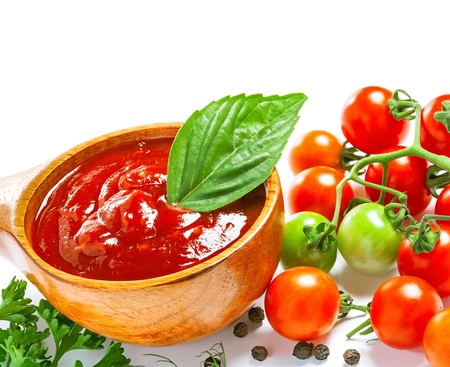 Red tomato sauce in a wooden spoon and ingredients, isolated in whiteの写真素材