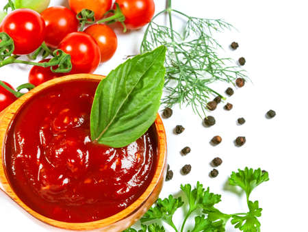 Red tomato sauce in a wooden spoon and ingredients, isolated in whiteの写真素材