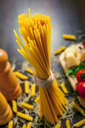Raw pasta spaghetti with sauce ingredients on tableの写真素材