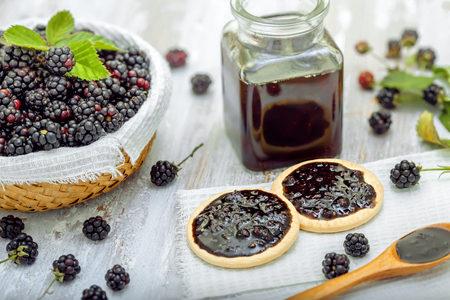 Fresh blackberries with jam sandwich biscuits on tableの写真素材
