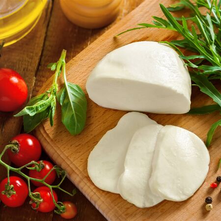 Sliced mozzarella, tomatoes and arugula on table, top viewの写真素材