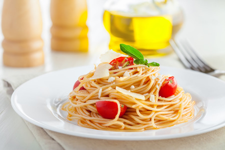 Italian spaghetti with tomato sauce, parmesan cheese and basil on tableの写真素材