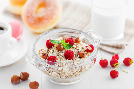 Oatmeal with raspberry and hazelnut. Breakfast with coffee on table.の写真素材