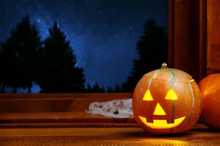 Halloween Jack O Lantern pumpkin indoor, night sky full of stars outsideの写真素材