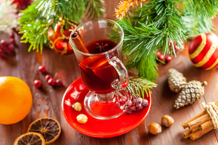 Glass of traditional hot drink on table by Christmas tree with decorations. Mulled wine.の写真素材