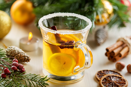 Glass of traditional hot drink on table by Christmas tree with decorations. Citrus tea.の写真素材