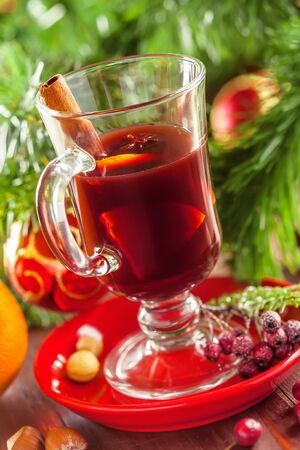Glass of mulled wine by Christmas tree with decorations. Delicious drink for party.の写真素材