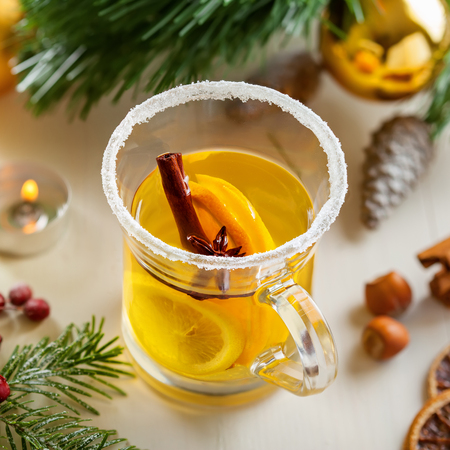 Holiday winter hot citrus drink near Christmas tree with decorations. Lemon tea. Top view.の写真素材