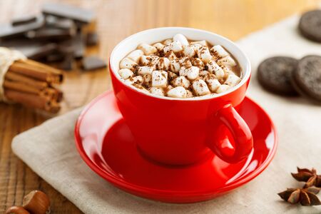 Cup of hot chocolate with marshmallow on table. Cocoa drink with sweet sandwich cookies.の写真素材