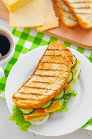 Sandwich with cheese, lettuce and vegetables for breakfast with coffee, top viewの写真素材