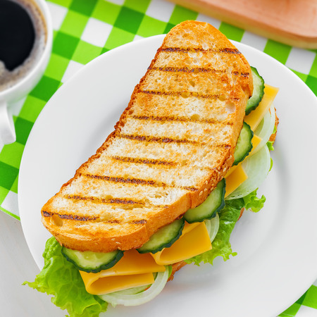 Sandwich with cheese, lettuce and vegetables for breakfast with coffee, top viewの写真素材