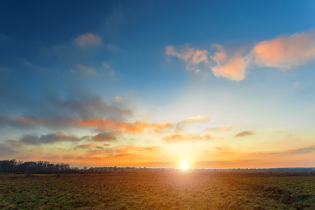 Sunset sky above field, spring season landscapeの写真素材
