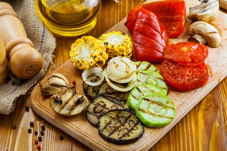 Grilled vegetables: tomato, corn, eggplant, mushroom, bell pepper, marrow and onion. Delicious healthy food on a table. Close-up shot.の写真素材