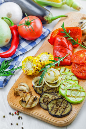Grilled vegetables meal and ingredients on a table. Tomato, corn, eggplant, mushroom, bell pepper, marrow and onion prepared on a barbecue. Healthy food.の写真素材