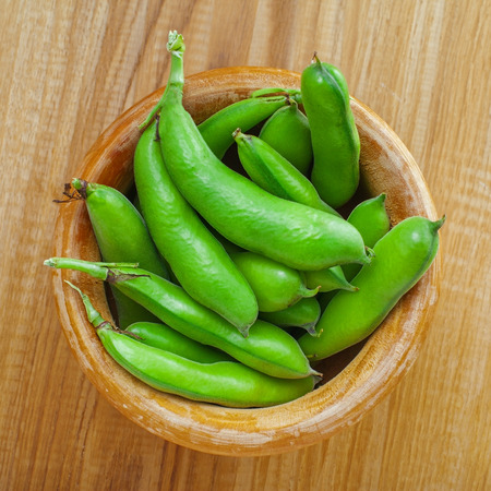 Bowl of fresh podded broad beans on a wooden table. Healthy organic food.の写真素材