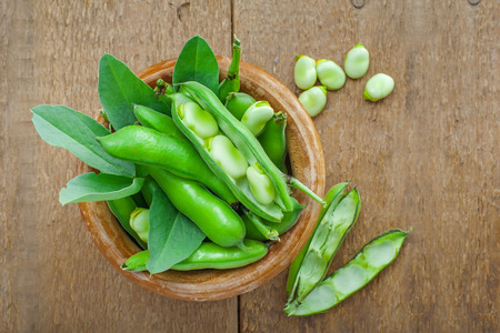 Bowl of fresh podded broad beans on a wooden table. Healthy organic food. Top view.の写真素材