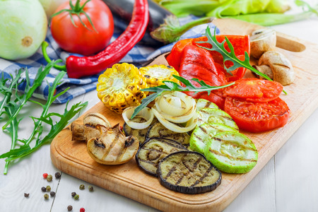 Vegetables roasted on a grill: tomato, corn, eggplant, mushroom, bell pepper, marrow and onion. Delicious healthy food and ingredients on a table. Close-up shot.の写真素材