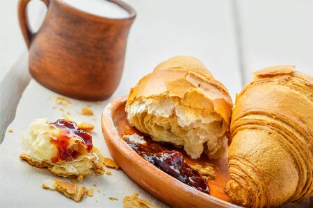 Croissant with fruit jam and fresh milk for breakfast. Delicious French meal on a table.の写真素材