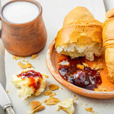 French food for healthy breakfast on a table. Croissants with fruit jam and glass of milk.の写真素材