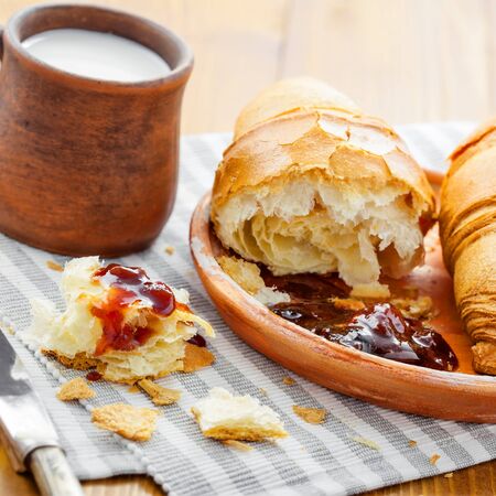 Authentic French croissants with jam and milk for breakfast on a table. Traditional European healthy meal.の写真素材