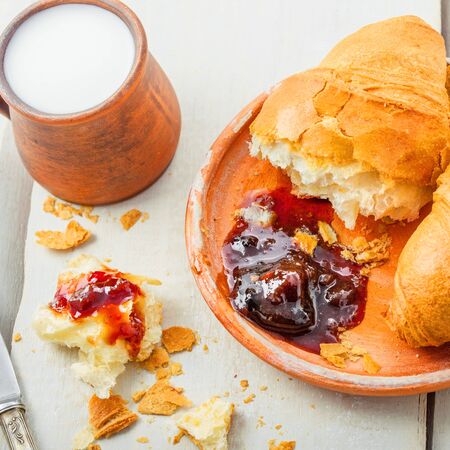 Breakfast with French croissants, fruit jam and milk on a table. Delicious European healthy food.の写真素材