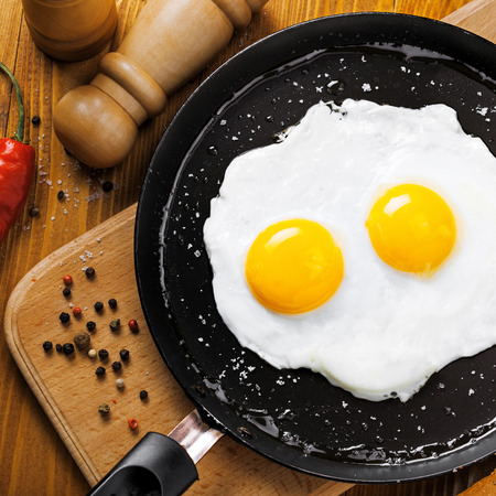 Two fried eggs in a frying pan cooked for breakfast. Delicious international meal on a table. Homemade food, top view.の写真素材