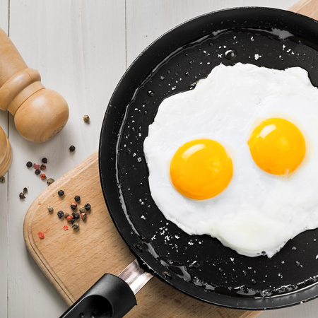 Two fried eggs in a frying pan cooked for breakfast. Delicious international meal on a table. Homemade food, top view.の写真素材