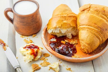 French food for healthy breakfast on a table. Croissants with fruit jam and glass of milk.の写真素材