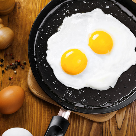 Delicious healthy simple breakfast meal made of eggs on a frying pan ready. Traditional homemade quick breakfast. International cuisine food. Top view.の写真素材