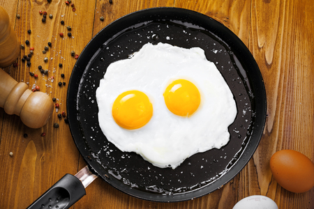 Fried eggs for delicious healthy easy breakfast on a table. Fresh homemade meal on a frying pan. Traditional breakfast food. International cuisine food.  Top view.の写真素材