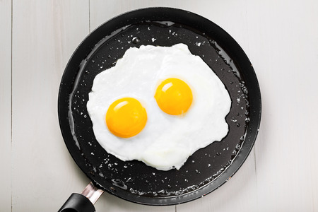 Fried eggs for delicious healthy easy breakfast on a table. Fresh homemade meal on a frying pan. Traditional breakfast food. International cuisine food.  Top view.の写真素材