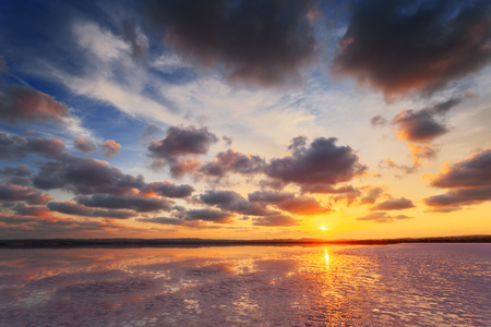 Sunset sky with clouds above salt lake. Beautiful sunny landscape.の写真素材