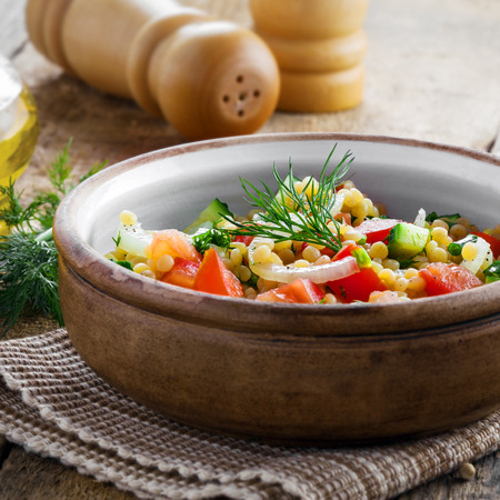 Traditional Israeli healthy meal Ptitim with tomatoes, cucumber and onion for delicious healthy breakfast. Classic Moroccan couscous with vegetables.の写真素材