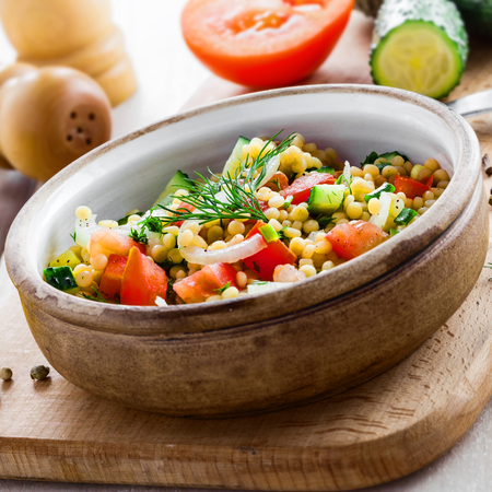 Delicious Israeli couscous Ptitim with vegetables on a white wooden table. Cooking of healthy vegetarian food for the meal. Traditional Moroccan cuisine.の写真素材