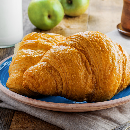 Croissant, jam, fresh fruits, coffee and bottle of milk on a table. Delicious French meal for healthy breakfast. Traditional European food.の写真素材
