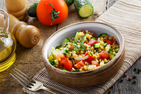 Healthy salad for breakfast made of couscous, tomatoes, cucumber and onion on a table. Traditional Israeli Ptitim meal. Moroccan cuisine food.の写真素材
