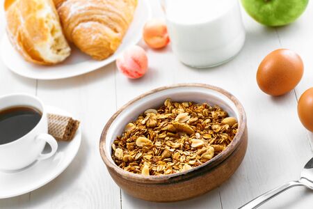 Granola, croissant, milk and fruits on a table. Healthy breakfast with coffee. International vegetarian meal. Top view.の写真素材