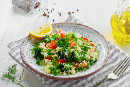 Delicious healthy meal made of couscous, broccoli and other vegetables on a rustic white wooden table. Traditional eastern food.の写真素材