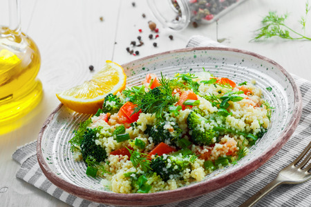 Traditional eastern couscous with broccoli, tomato, pepper, onion and dill on a plate for healthy meal. Moroccan healthy food on a table. Close-up shot.の写真素材