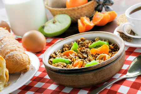 Granola, croissant, eggs, milk and fruits on a red checkered tablecloth. Healthy breakfast with coffee. International vegetarian meal. Close-up shot.の写真素材