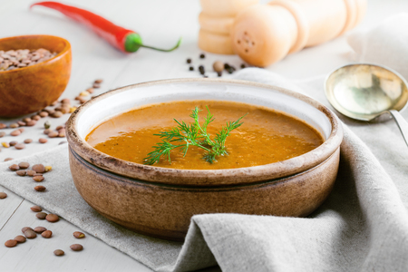 Lentil soup in a rustic bowl on a cotton canvas tablecloth. Healthy vegetarian food on a white wooden table.の写真素材