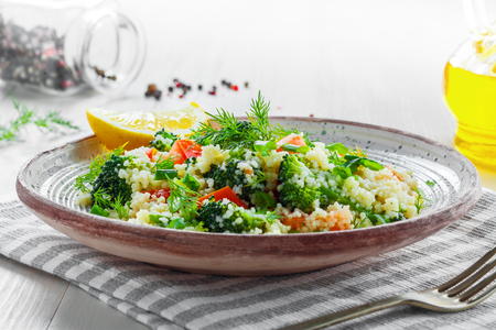 Delicious healthy meal made of couscous, broccoli and other vegetables on a rustic wooden table. Traditional eastern food. Close-up shot.の写真素材