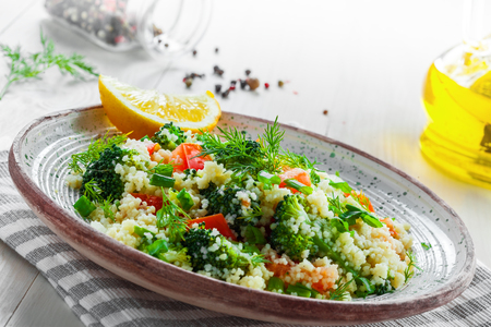 Healthy salad made of couscous, broccoli, tomato, pepper, onion and dill on a table. Traditional Moroccan food for healthy meal. Close-up shot.の写真素材