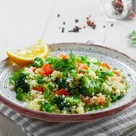 Vegetarian salad made of couscous, broccoli, tomato, pepper, onion and dill on a plate. Traditional Moroccan food for healthy meal on a table.の写真素材
