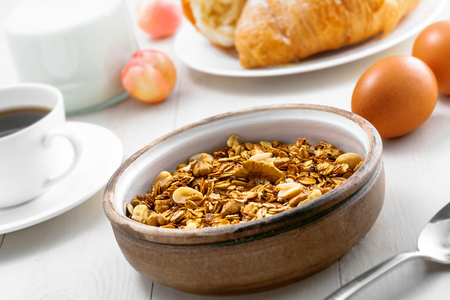 Granola, croissant, milk and fruits on a table. Healthy breakfast with coffee. International vegetarian meal.の写真素材