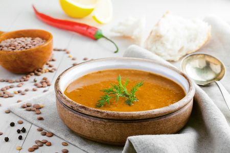 Bowl of delicious lentil soup with bread and lemon slice on a white wooden table. Traditional healthy vegetarian food.の写真素材