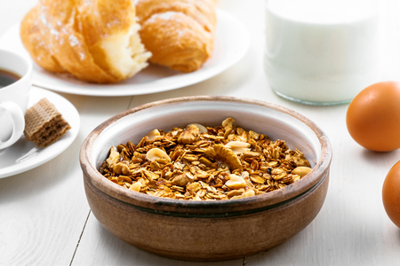 Delicious healthy breakfast with oatmeal granola, coffee and croissant on a white wooden table. Traditional healthy food. Close-upの写真素材