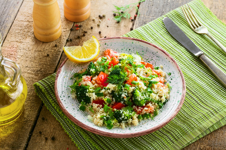 Healthy salad made of couscous, broccoli, tomato, pepper, onion and dill on a table. Traditional Moroccan food for healthy meal. Top view.の写真素材