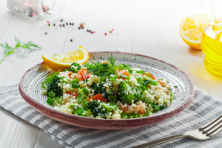 Traditional Moroccan couscous with broccoli, tomato and other vegetables on a plate. Eastern meal for healthy lunch on a table.の写真素材